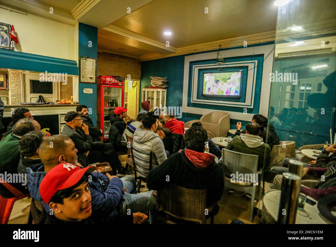 January 16, 2024: Tunis, Tunisia. 16 January 2024. Tunisian football fans watch the Tunisia vs Namibia match on a tv screen in Tunis. The match, which is being played at the Amadou Gon Coulibaly Stadium at Korhogo in Ivory Coast, is part of the Africa Cup of Nations (Credit Image: © Hasan Mrad/IMAGESLIVE via ZUMA Press Wire) EDITORIAL USAGE ONLY! Not for Commercial USAGE! Stock Photo