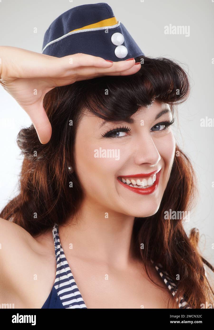 Travel, portrait and salute of a sailor, woman and model in studio isolated on a white background. Smile, pin up and face of vintage air hostess in Stock Photo