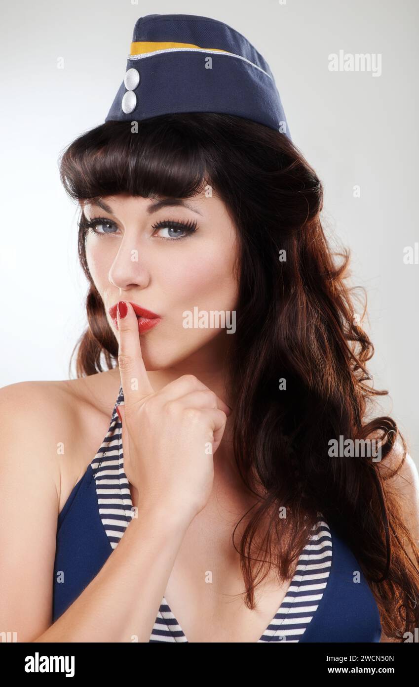 Travel portrait, silence and a sailor woman, model or girl in studio isolated on a white background. Finger on lips, face of vintage person in hat and Stock Photo