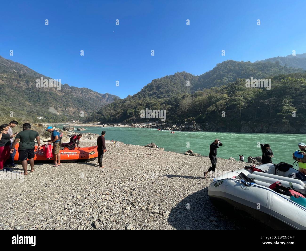 A group of individuals gathered near a cluster of rafts floating on ...