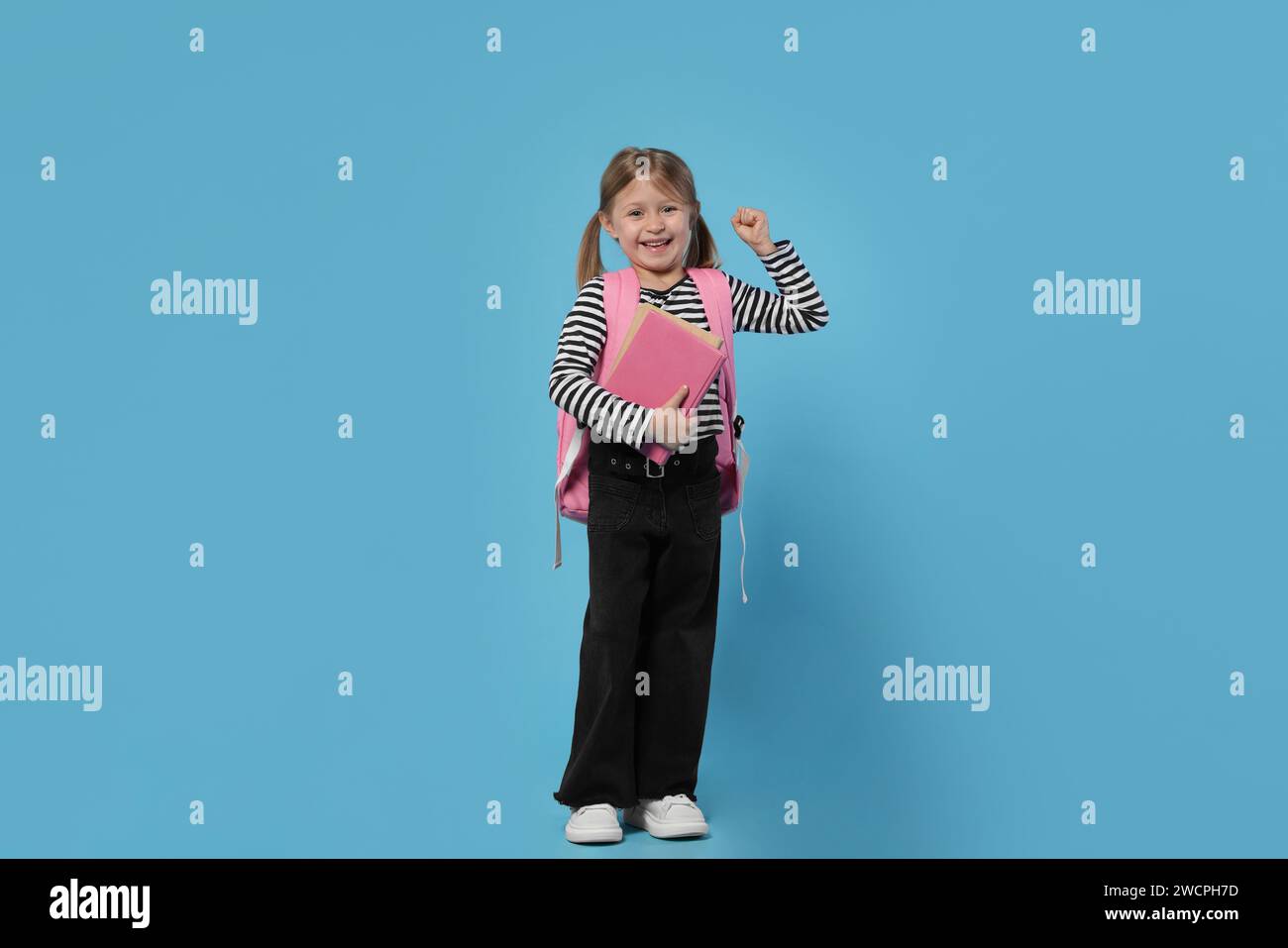 Happy schoolgirl with backpack and books on light blue background Stock ...