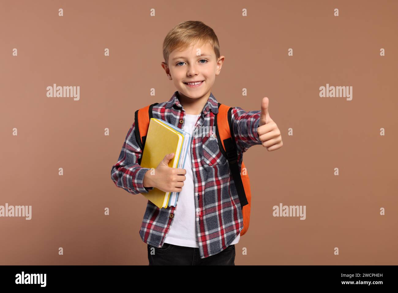 Happy schoolboy with backpack and books showing thumb up gesture on ...