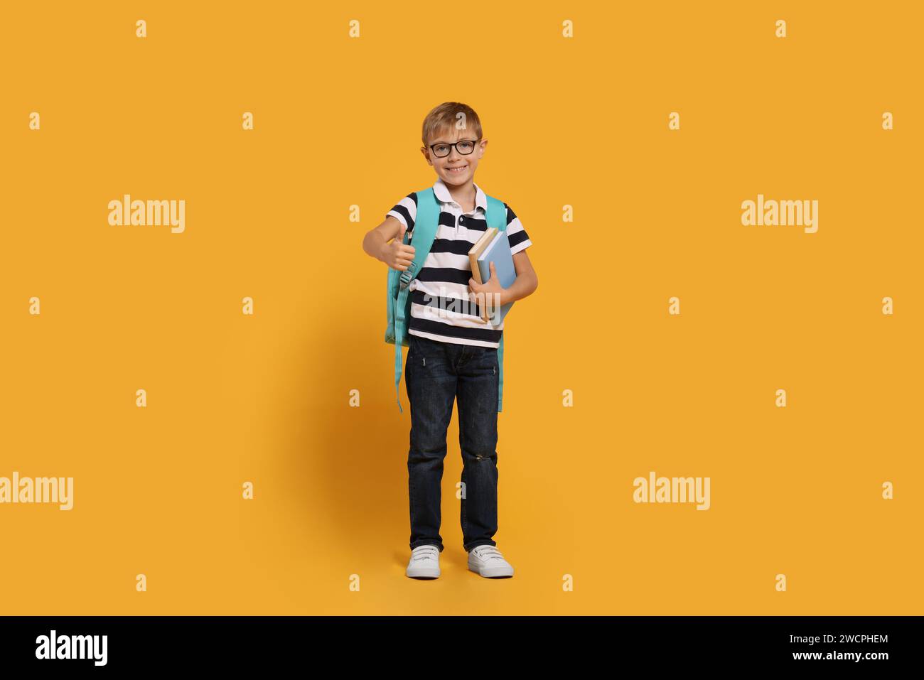 Happy schoolboy in glasses with backpack and books showing thumb up ...