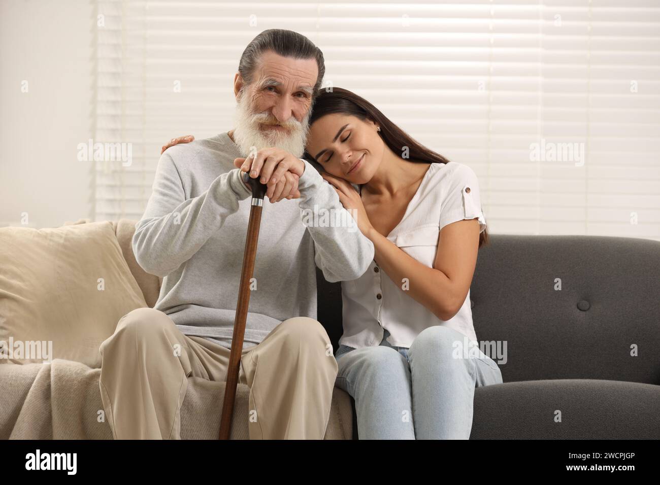 Senior man with walking cane and young woman on sofa at home Stock ...
