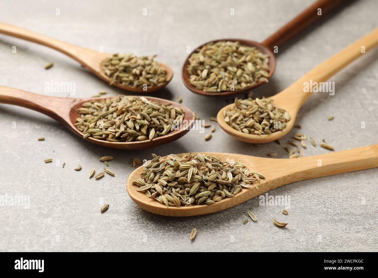 Wooden spoons with fennel seeds on grey table, closeup Stock Photo