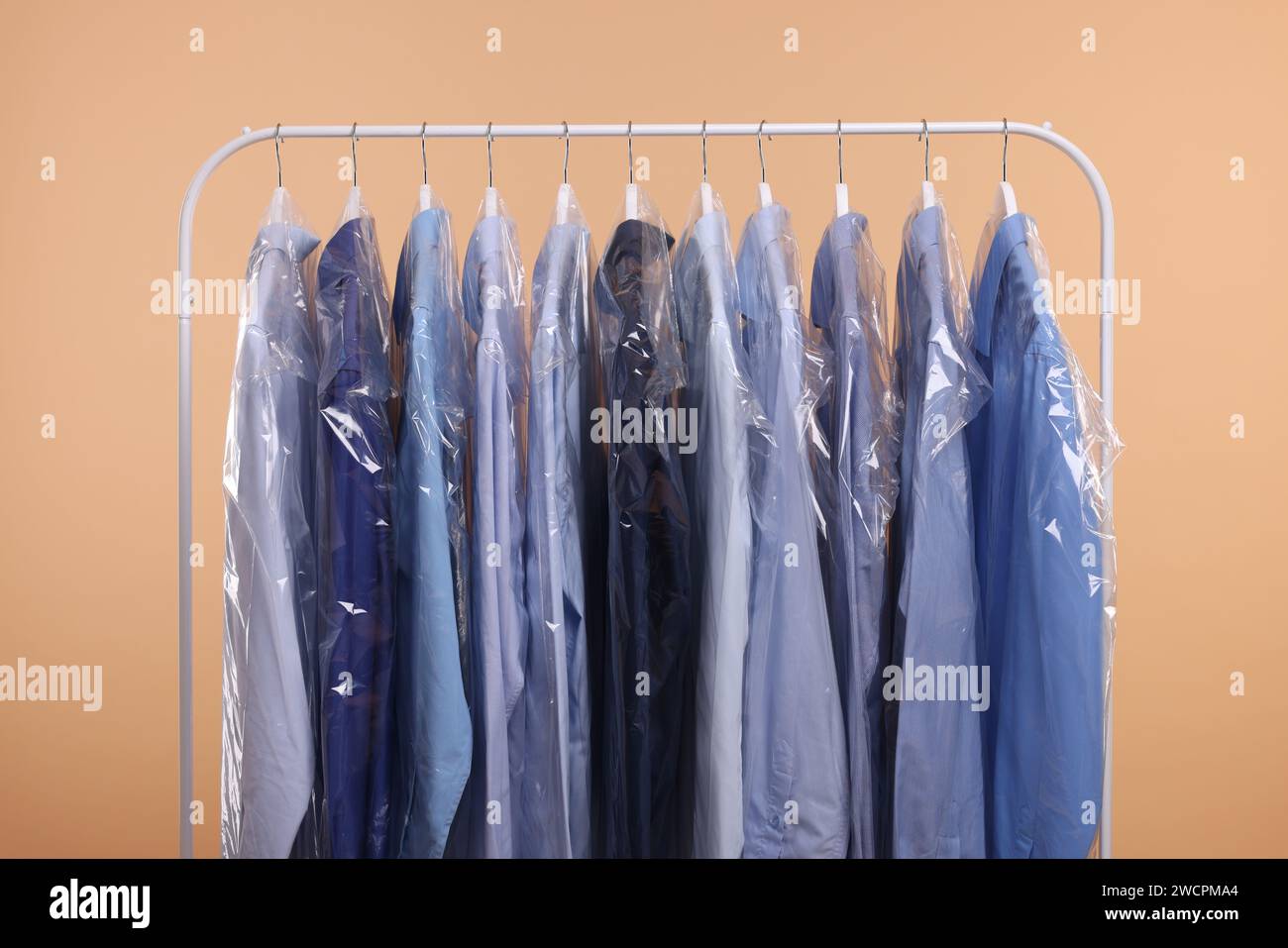 Drycleaning service. Many different clothes in plastic bags hanging on