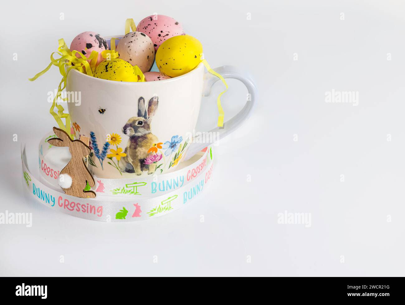 Easter eggs in a Easter theme cup on white background, copy space, Easter concept Stock Photo
