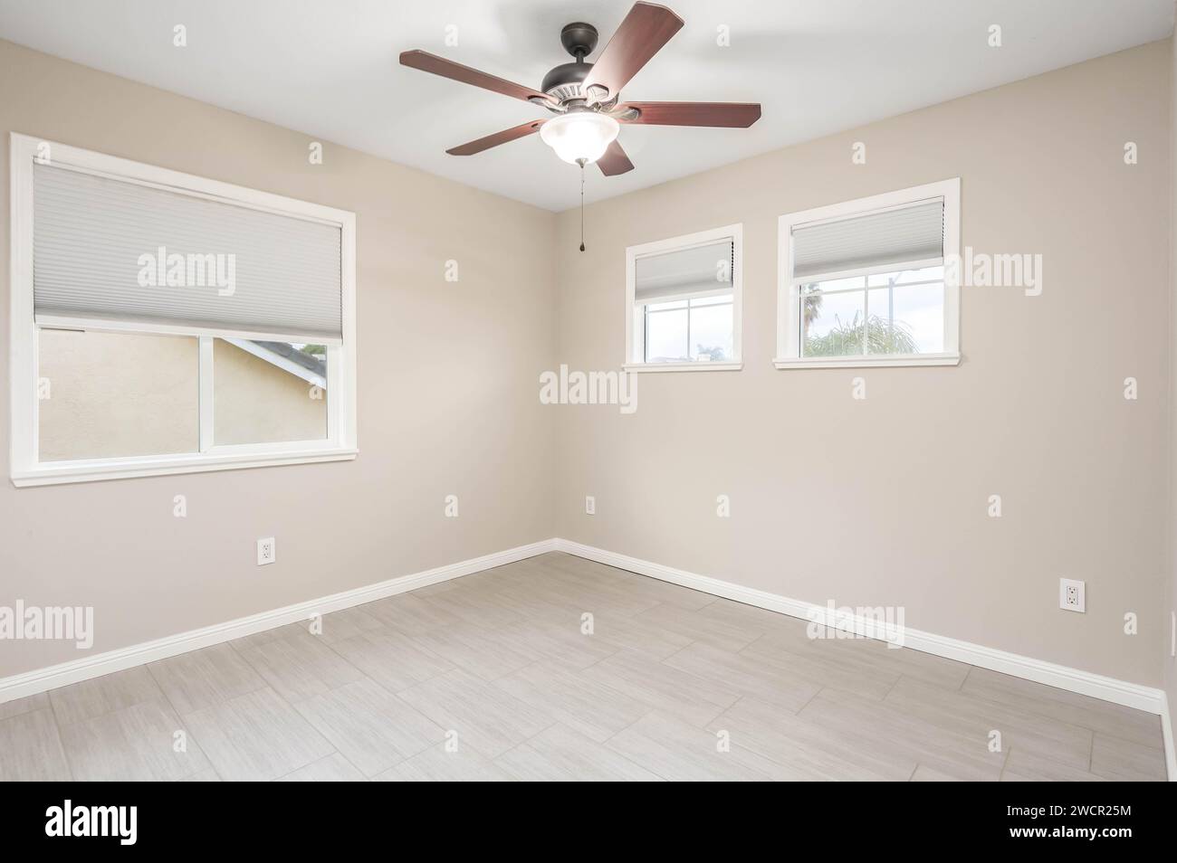 Empty Real Estate bedroom with bright walls, ceiling fan and windows. Great for virtual staging and real estate content Stock Photo