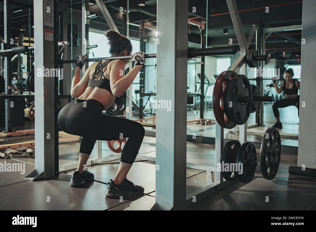 Sporty woman exercising with weight plate in the gym. Stock Photo