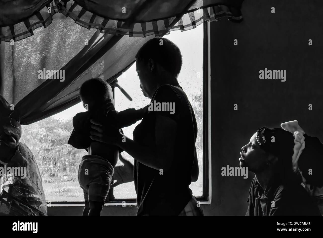 african family in the house watching the rain on the window poverty Stock Photo