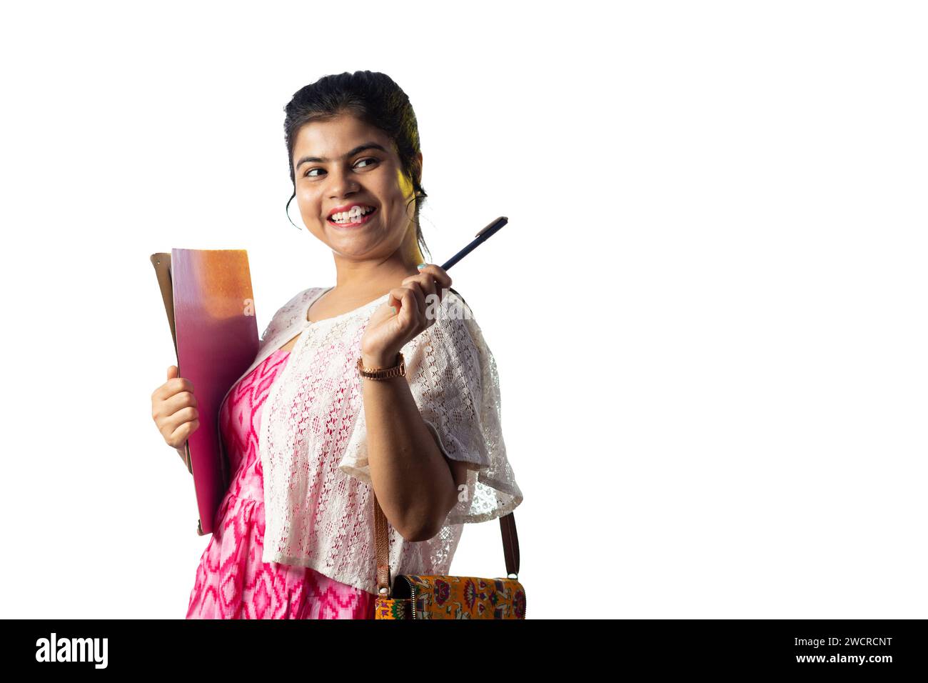 A pretty young Indian girl with books in hand pointing with smiling ...