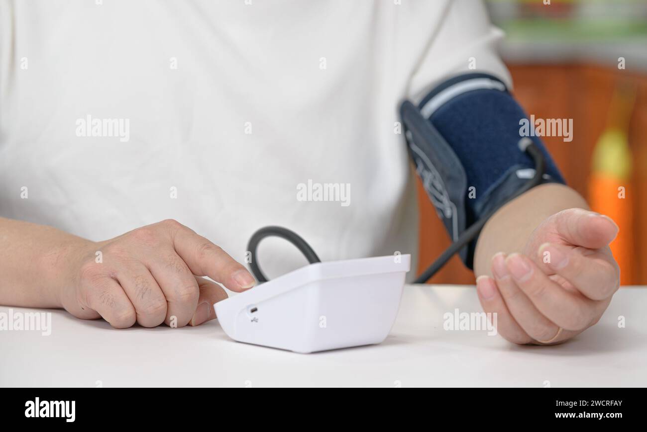 Middle-aged man using blood pressure monitor Stock Photo