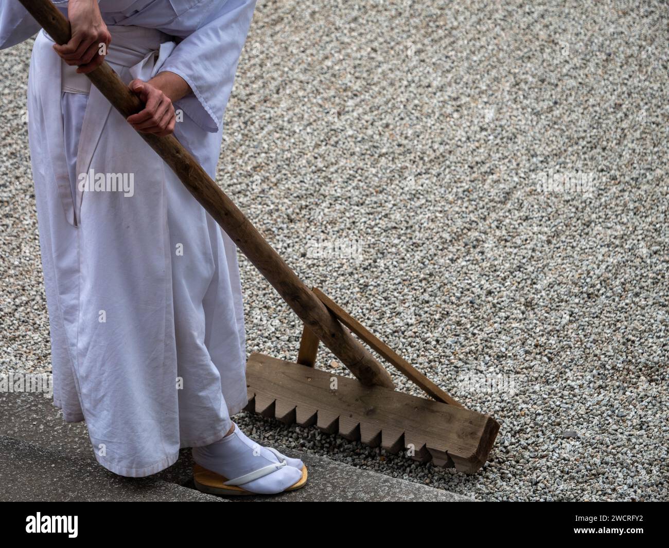 A monk rakes a gravel garden at Kasuga Taisha Shrine in Nara, Japan