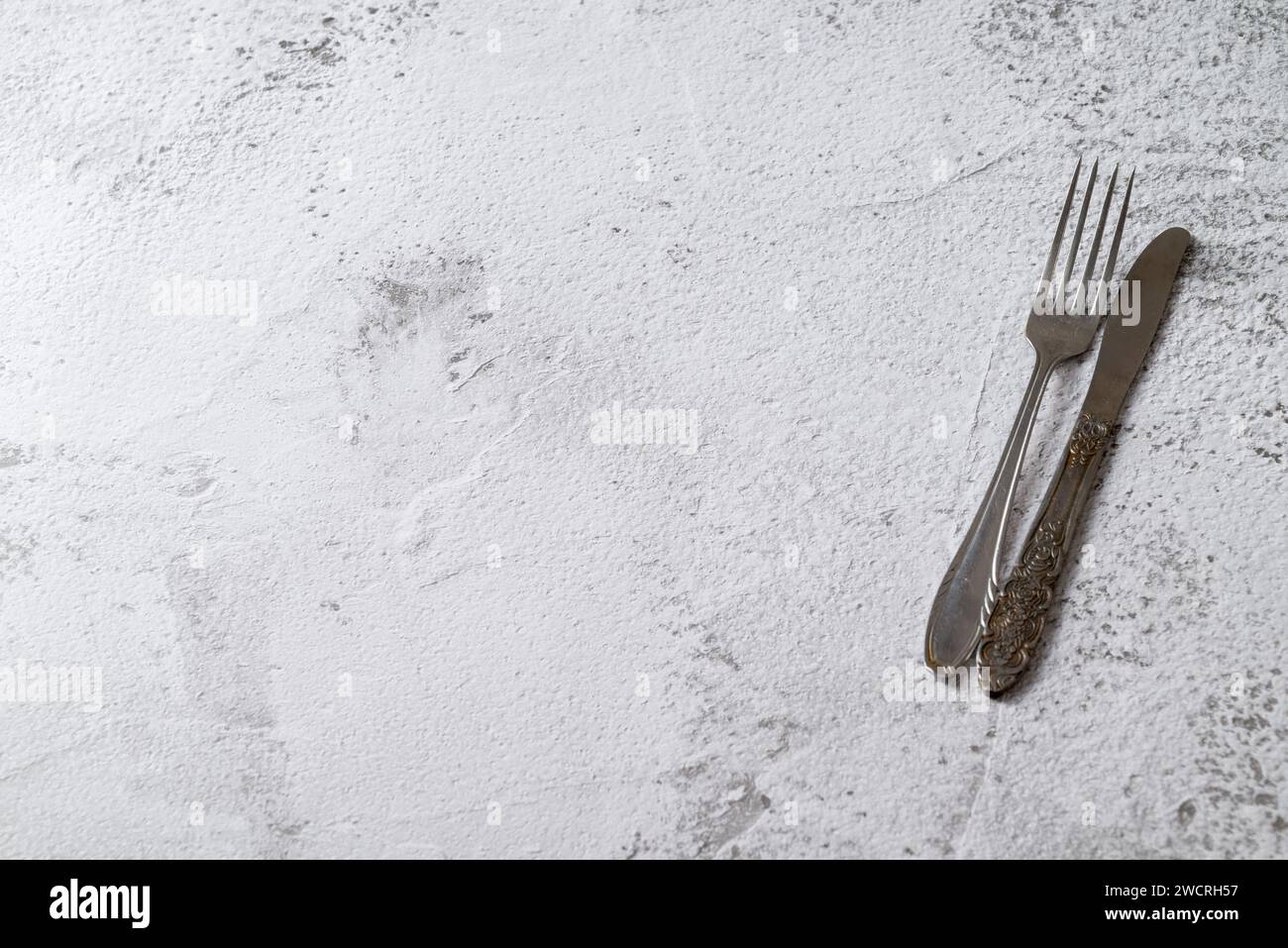 Antique fork and knife on white stone table Stock Photo