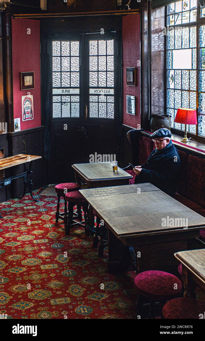 Mature man looking at his smart phone in traditional British pub in London , United Kingdom . Stock Photo