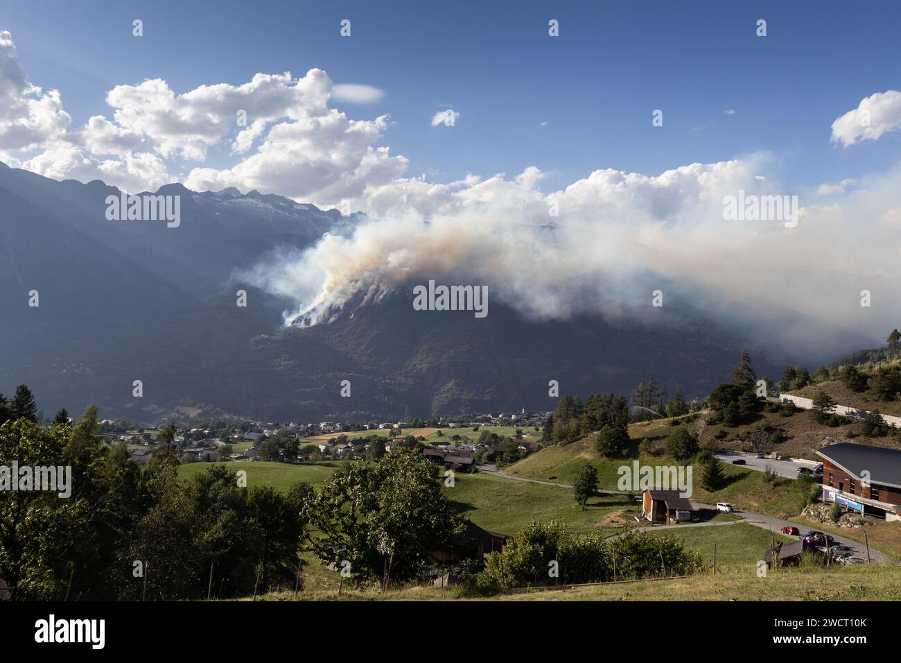 Forest fire engulfs the side of the Riederhorn moutain, near Brig in Switzerland with smoke filling the Rhone Valley. Real forest fire which occured i Stock Photo