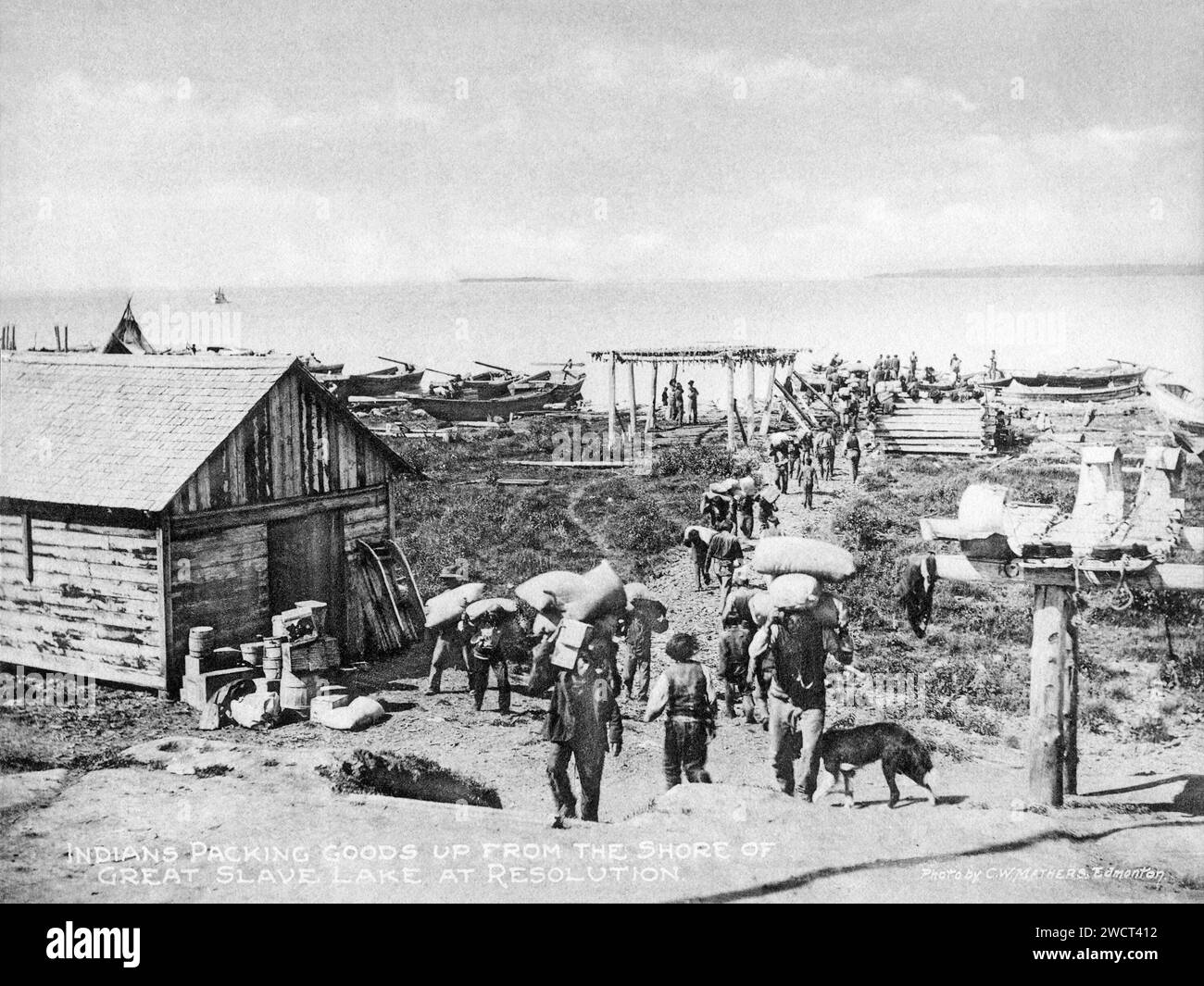 A 1901 photograph of supplies being unloaded at Fort Resolution on the Great Slave Lake in the Northwest Territories, taken by C W Mathers on an expedition to the far north of Canada and published in his book ‘The Far North’. Mathers captioned this photograph: Indians packing goods up from the shore of Great Slave Lake at Resolution. Stock Photo