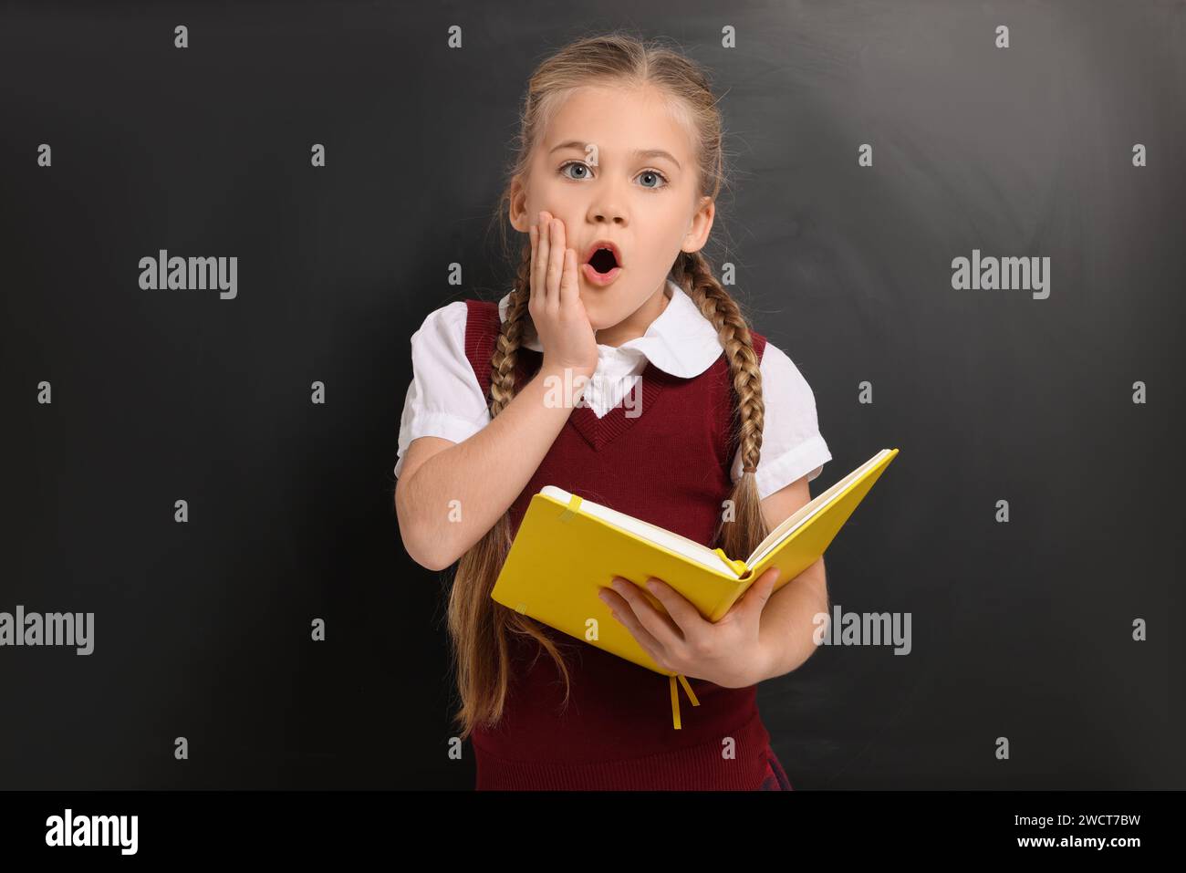 Emotional schoolgirl with open book near blackboard Stock Photo - Alamy