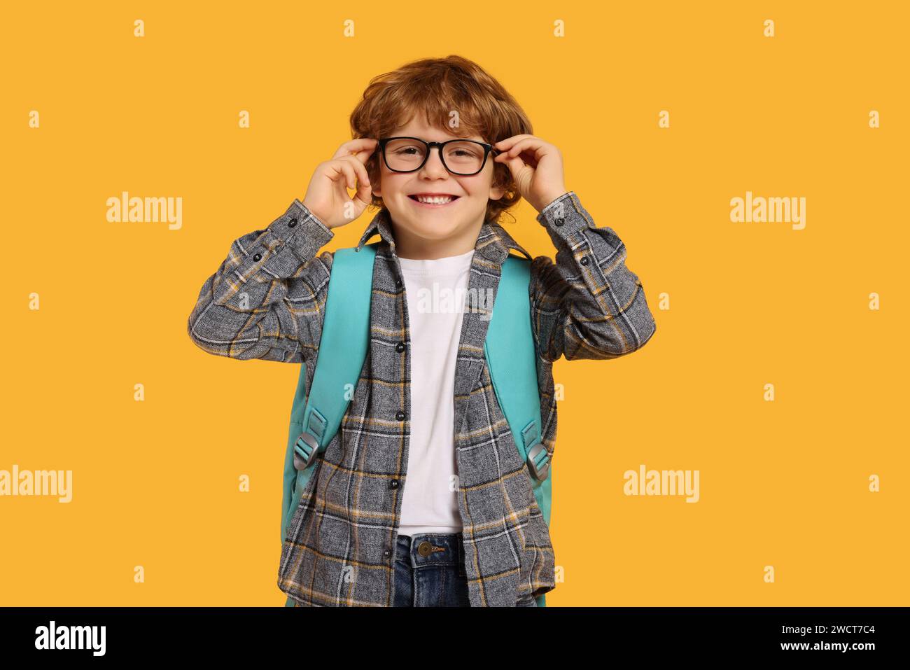 Happy schoolboy with backpack on orange background Stock Photo - Alamy