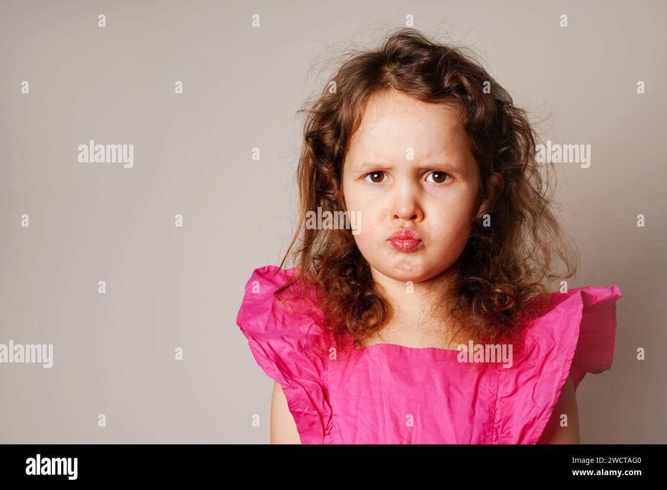 Beautiful angry little child girl looking at you. the child puffed out her cheeks Stock Photo