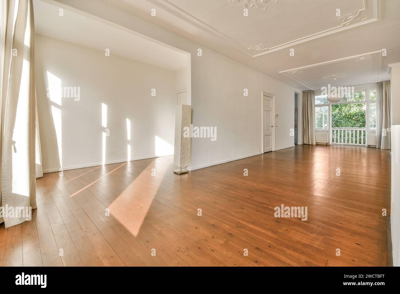 An empty, brightly lit room featuring polished hardwood flooring, large ...