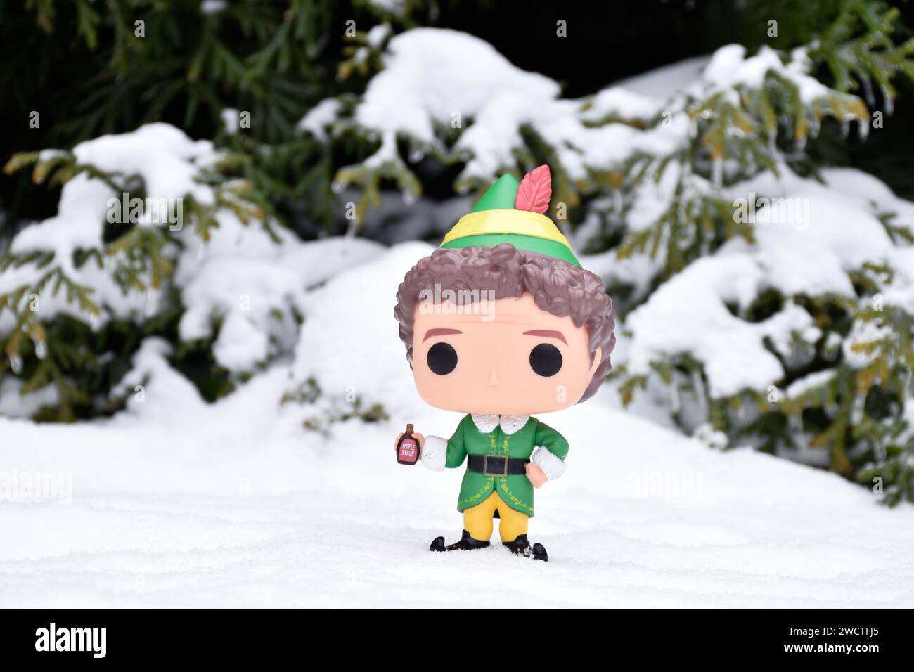 Funko Pop action figure of Buddy from Christmas comedy movie Elf. Winter forest, snow drifts, snowy pine branches, green woods. Stock Photo