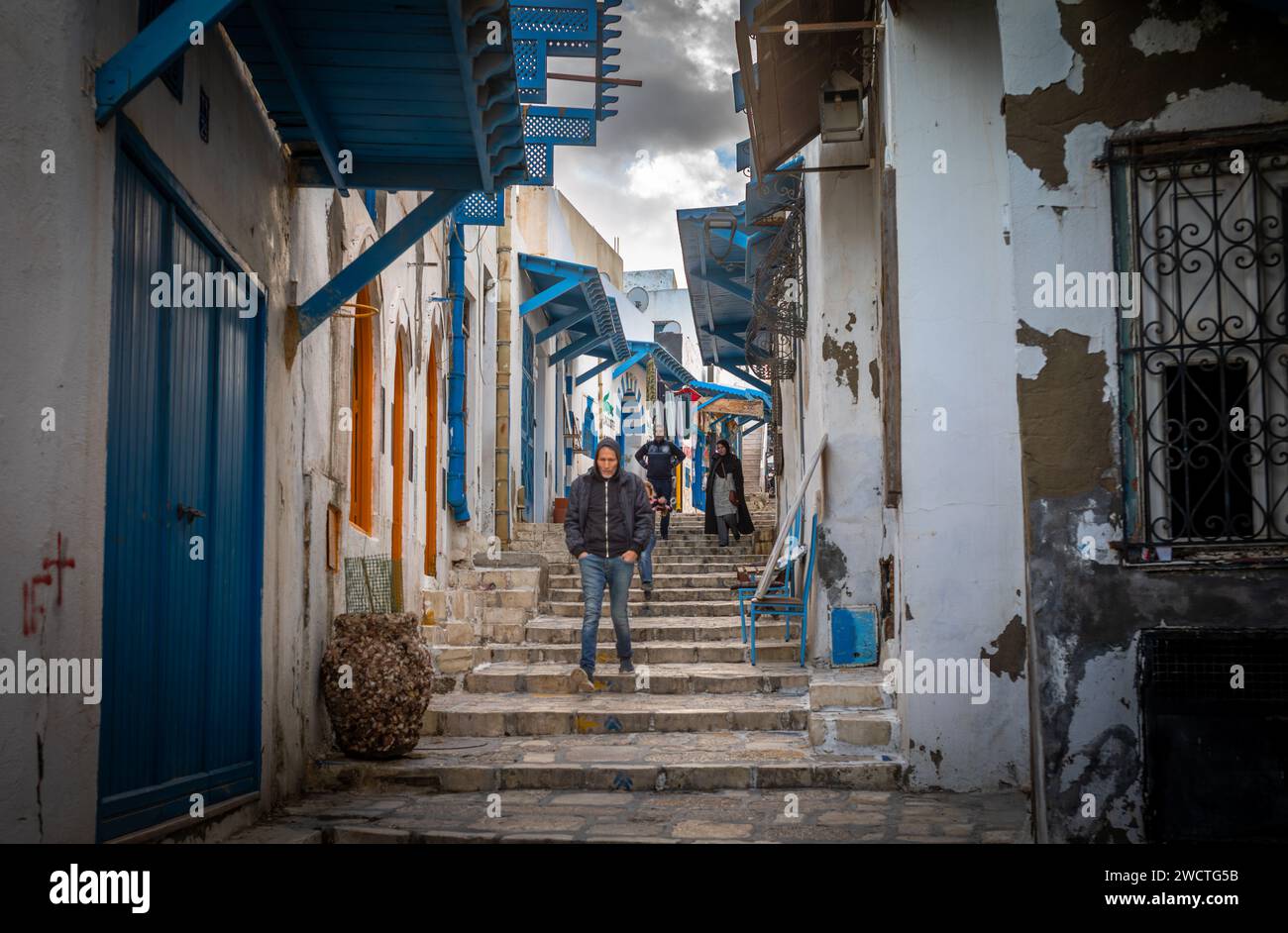 A man walks down steps in the Rue el Aghalba, a small cobbled street in the ancient medina, Sousse, Tunisia. The medina is a UNESCO World Heritage Sit Stock Photo