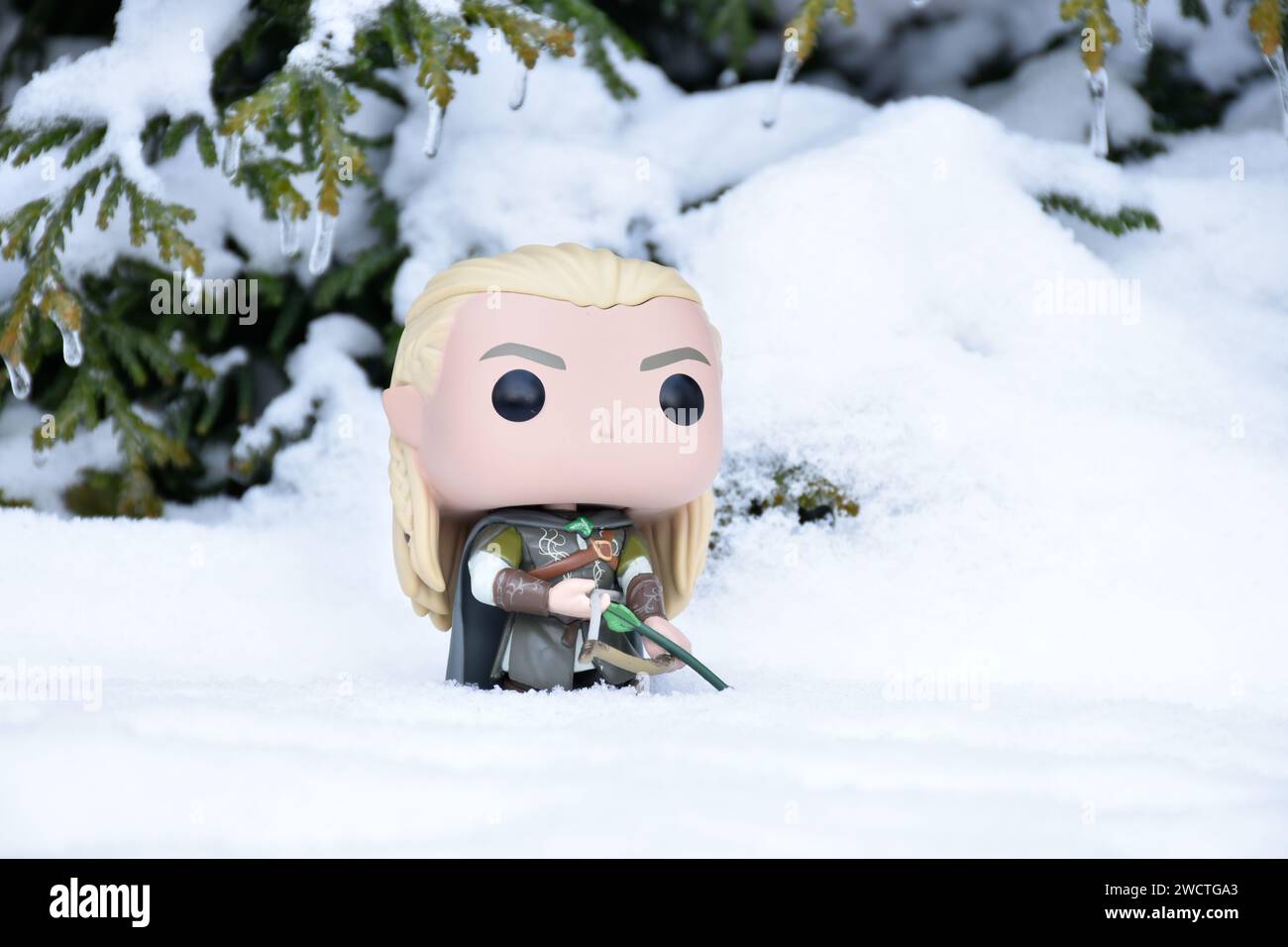 Funko Pop action figure of elf Legolas from fantasy movie The Lord of the Rings. Warrior holding bow and arrow. Winter forest, snow, green woods. Stock Photo
