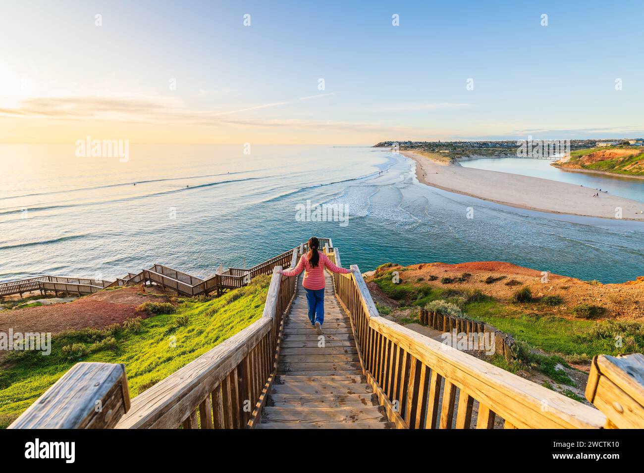 Woman gracefully descends the South Port Beach stairs captivated by the spectacular sea view during sunset, Port Noarlunga, South Australia Stock Photo