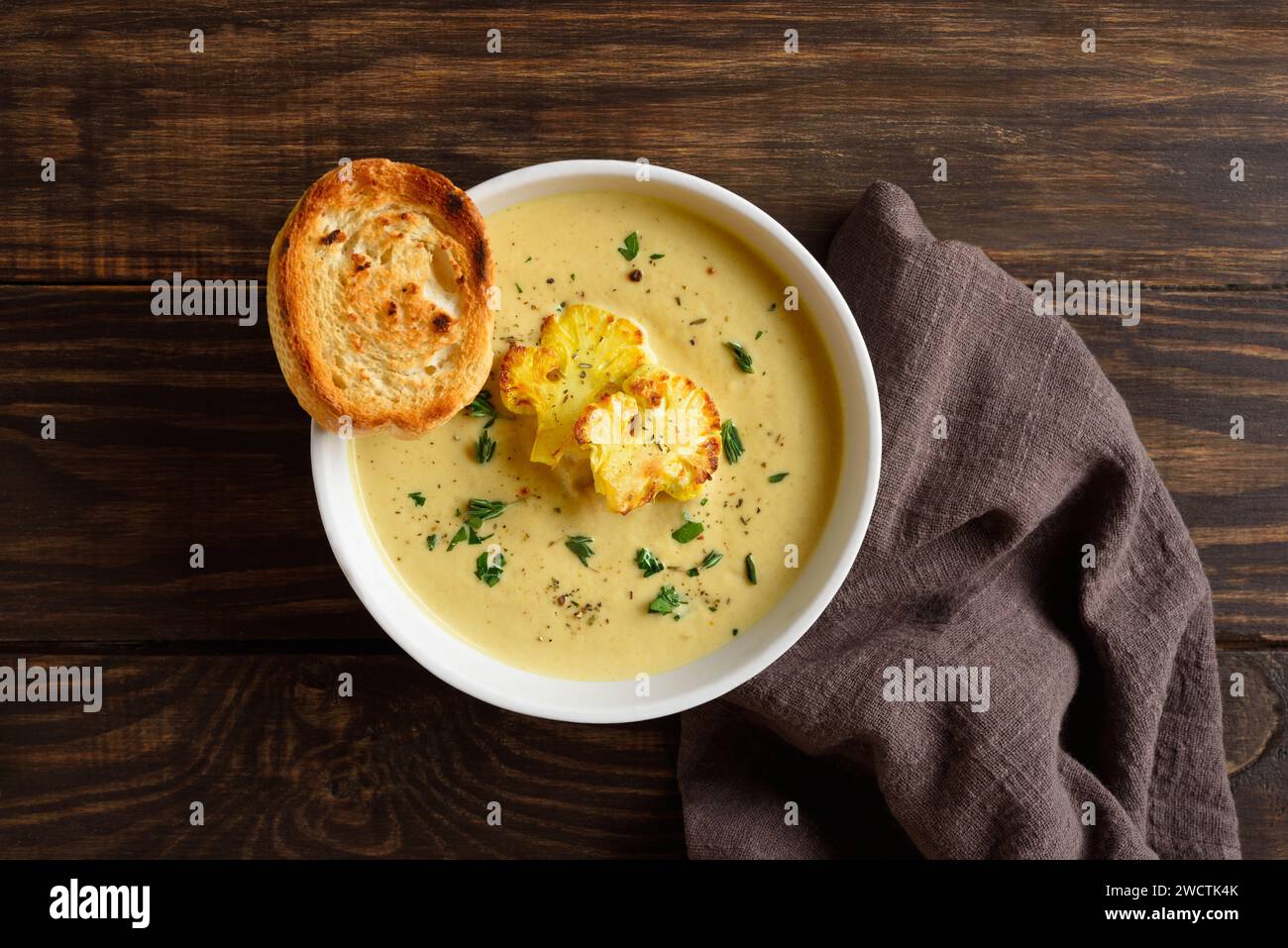 Cauliflower cheese soup in bowl over wooden background. Vegetarian or healthy diet food concept. Top view, flat lay Stock Photo