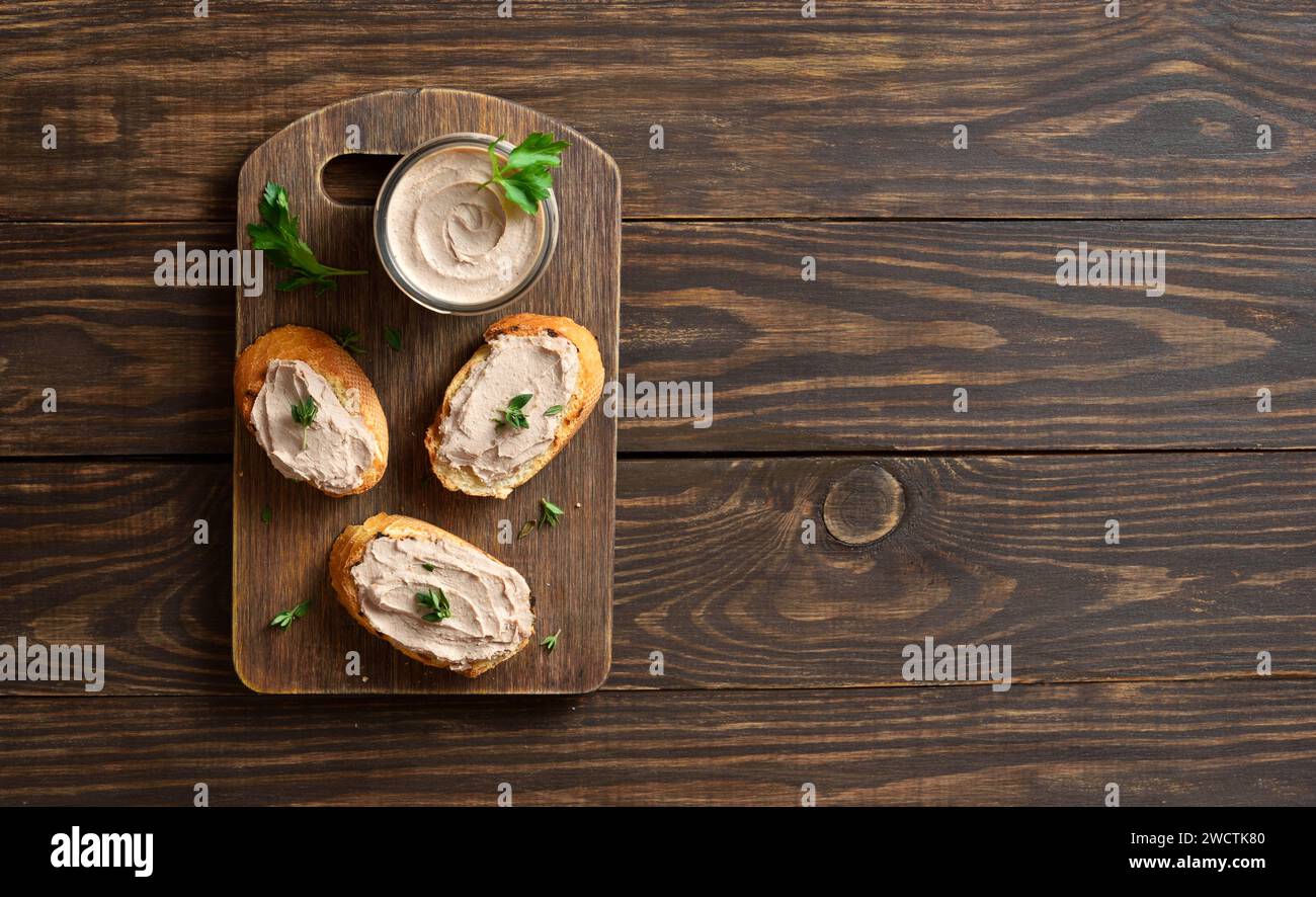 Toasted bread with chicken liver pate on cutting board over wooden background with free space. Top view, flat lay Stock Photo
