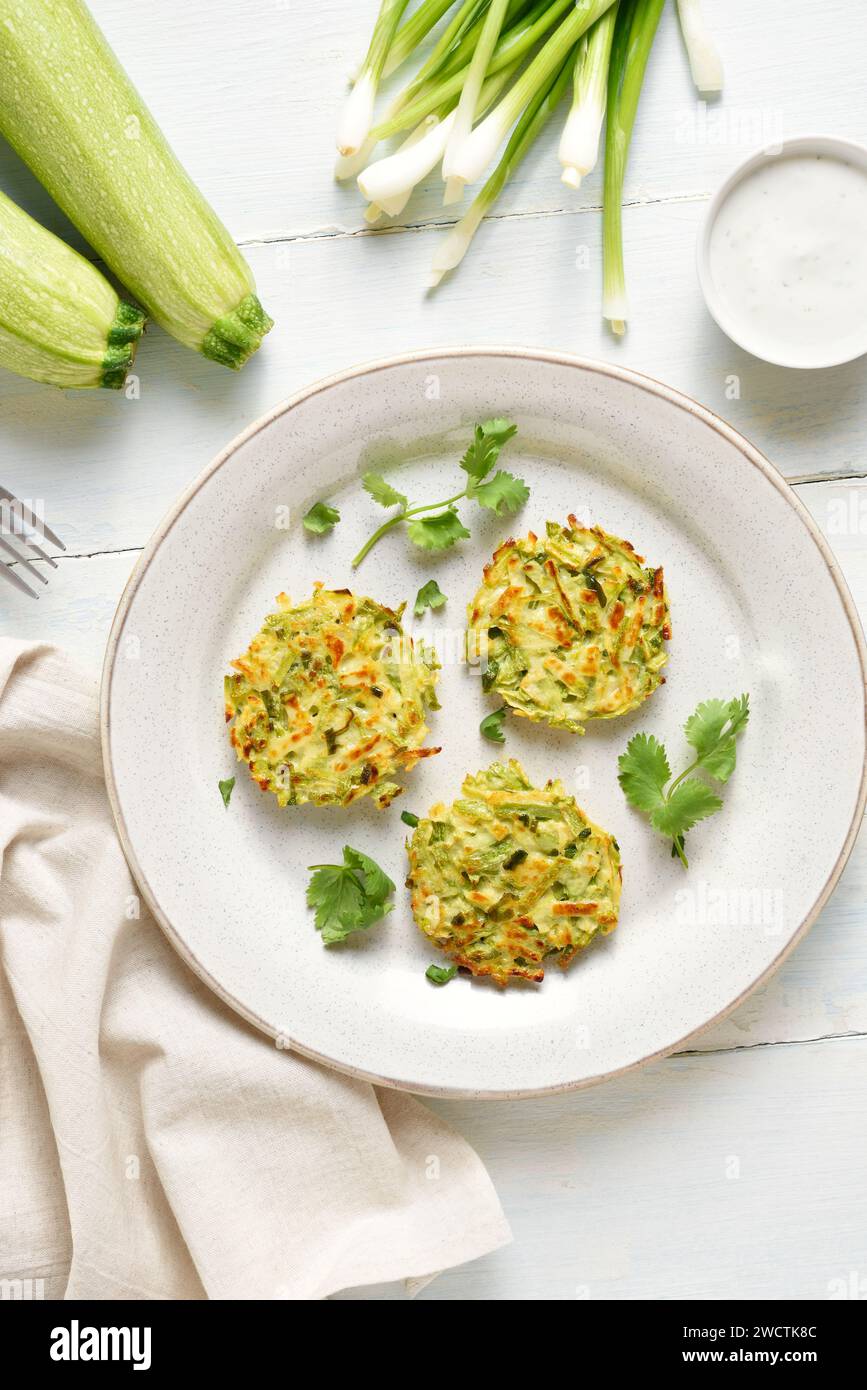 Zucchini fritters. Vegetable vegetarian zucchini pancakes on plate over light wooden background. Top view, flat lay Stock Photo