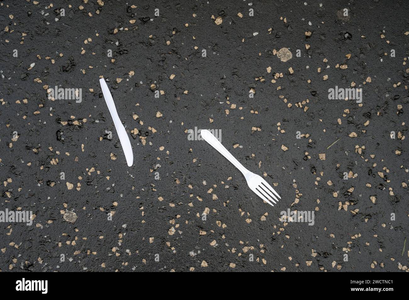 Plastic knife and fork discarded on a pavement Stock Photo