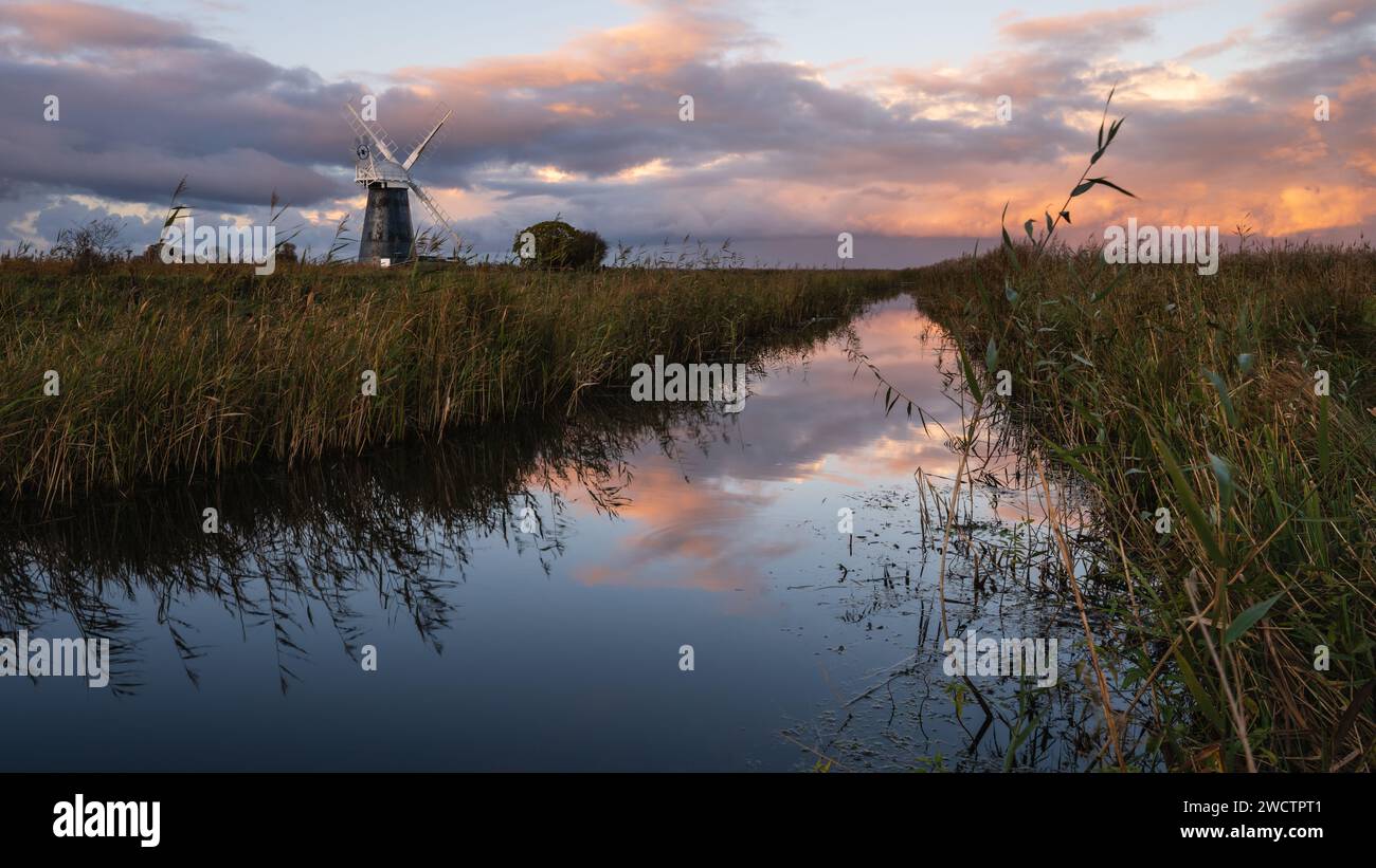 Colourful cloudy sky over Mutton's mill and reedbeds at Halvergate marshes in the Norfolk Broads i Mutton's Mill, November 2023 Stock Photo