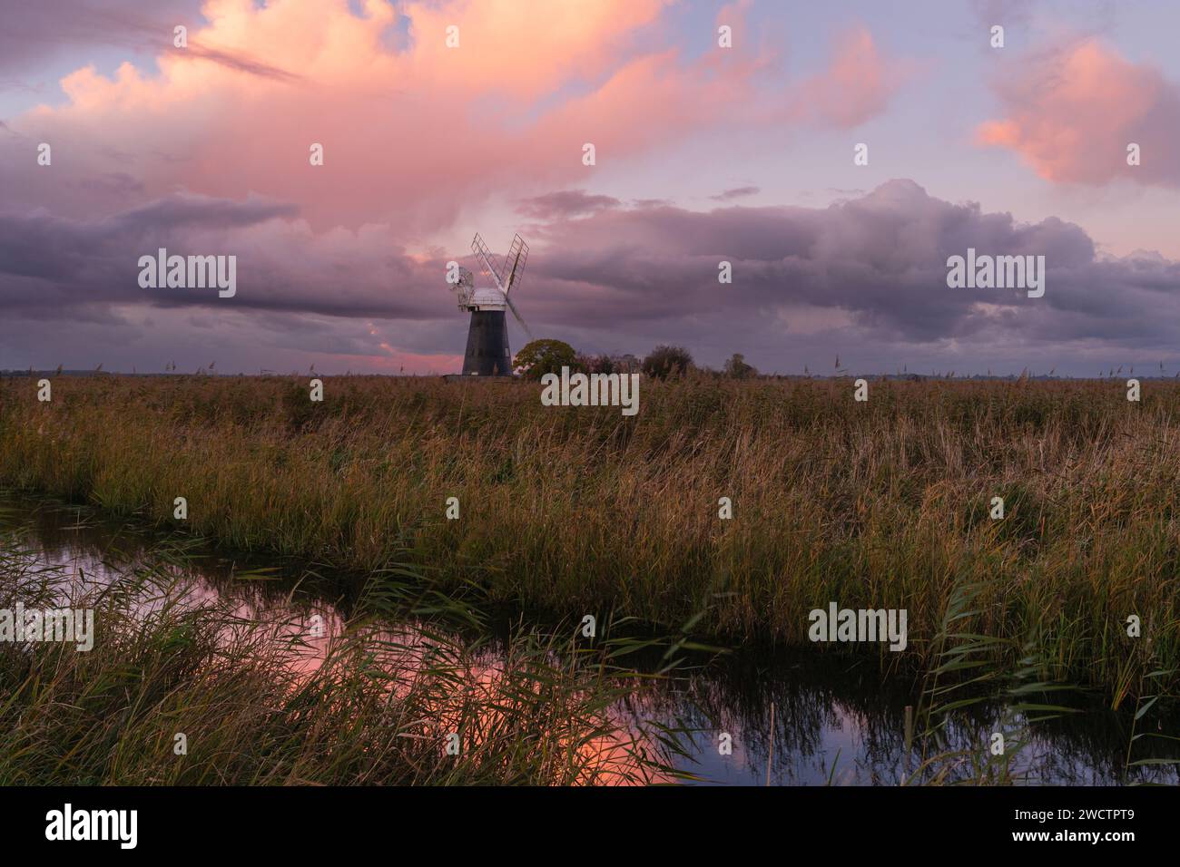 Colourful cloudy sky over Mutton's mill and reedbeds at Halvergate marshes in the Norfolk Broads ii Mutton's Mill, November 2023 Stock Photo
