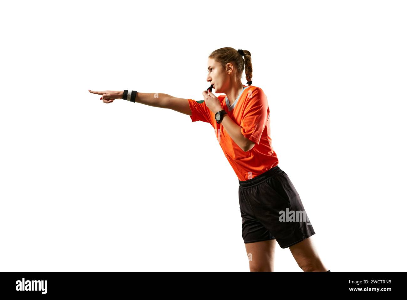 Young woman, football referee in uniform pointing and blowing whistle