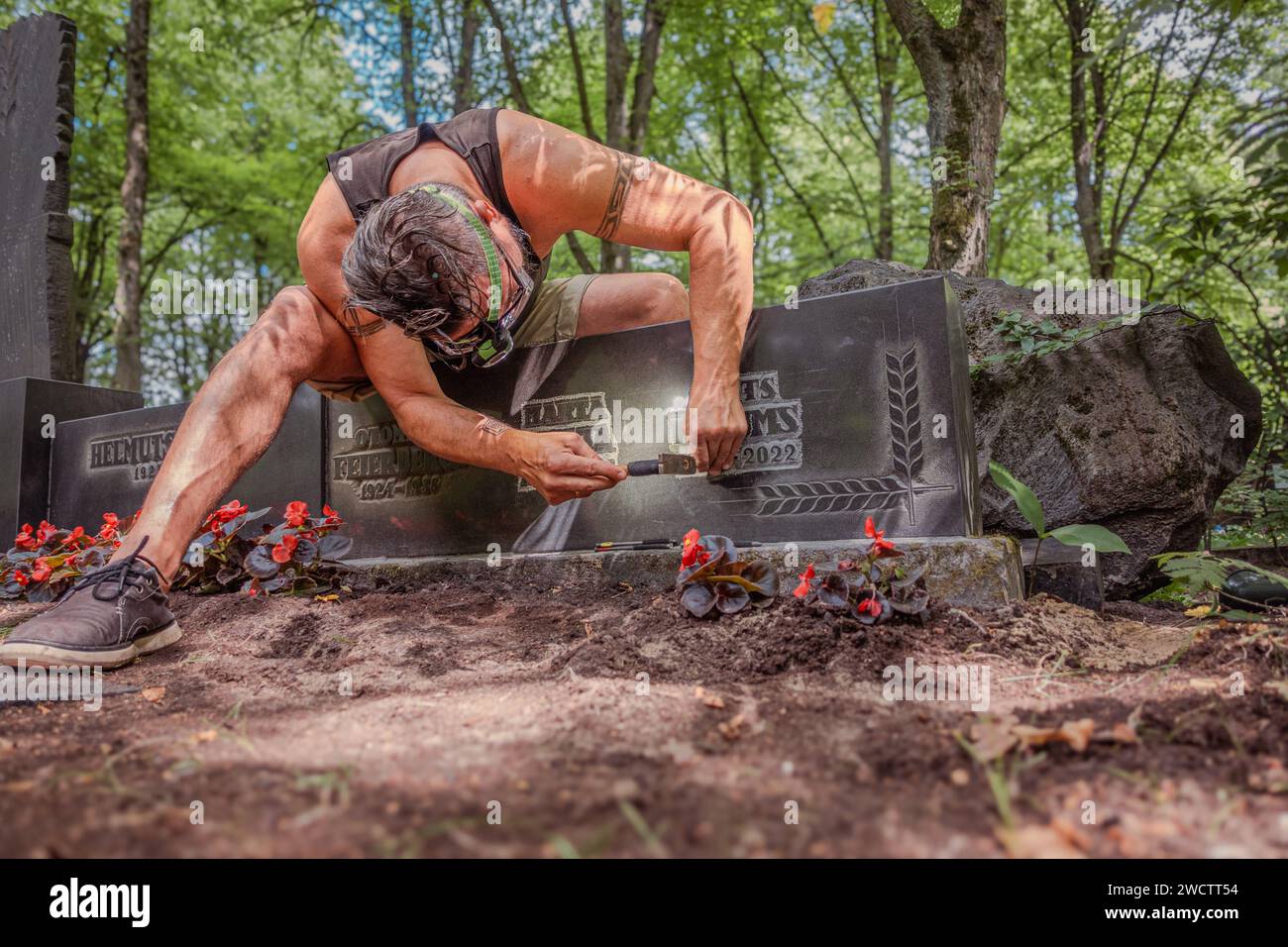 Stone engraver working in a cemetery carving letters on headstone with