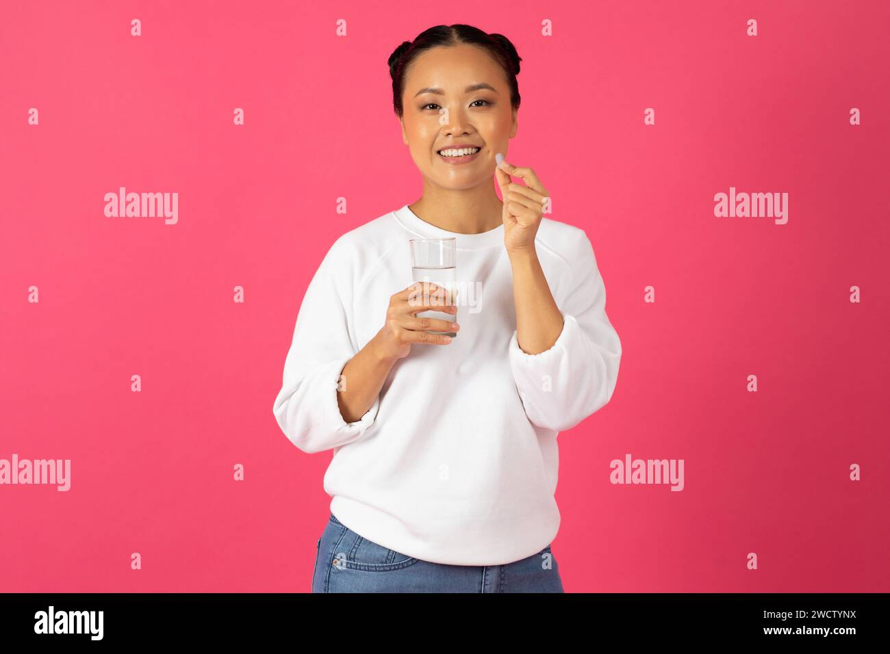 Happy Young Asian Lady Holding Glass Of Water And Beauty Supplement Pill Stock Photo