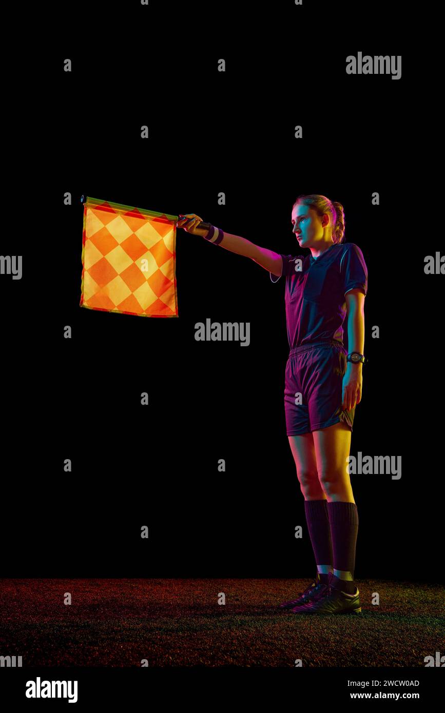Young woman, assistant referee raising flag up meaning offside position