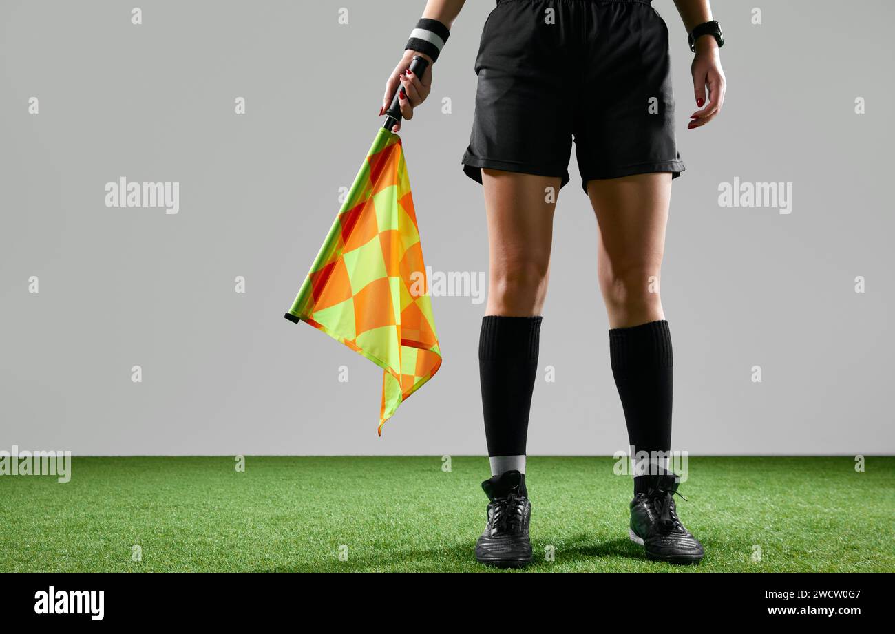 Cropped image of female legs, referee on field standing with flag to