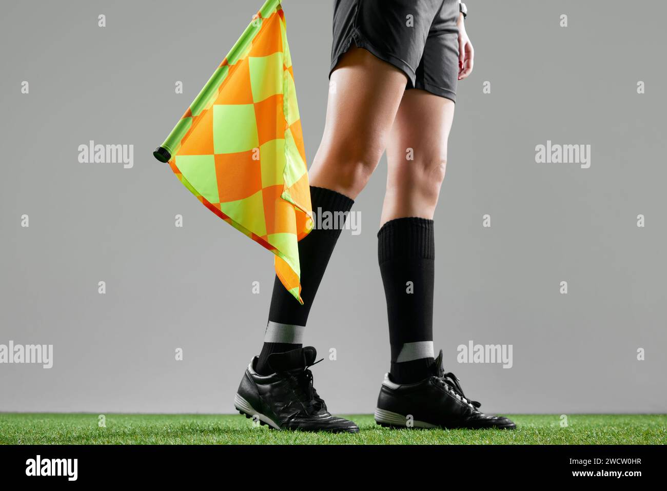 Cropped image of female legs, referee on field standing with flag to