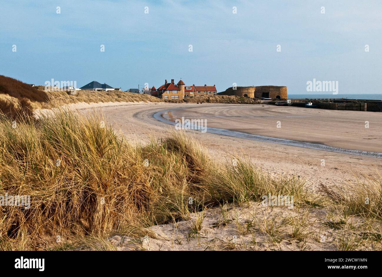Beadnell Harbour and Beach Northumberland Coast in March showing the limekilns, houses and harbour wall on a sunny day Stock Photo