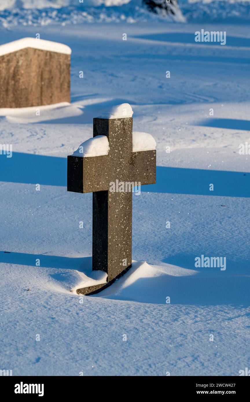 Graveyard with cross made of stone covered in snow Stock Photo