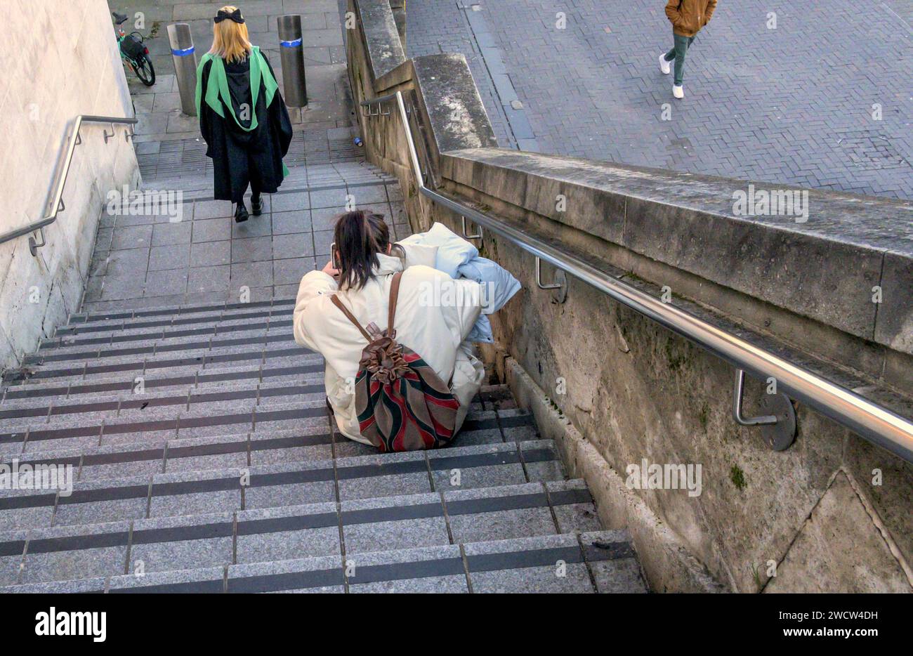 London, UK. People on steps on the South Bank. Oriental girl in graduation robe and another sitting on a step Stock Photo