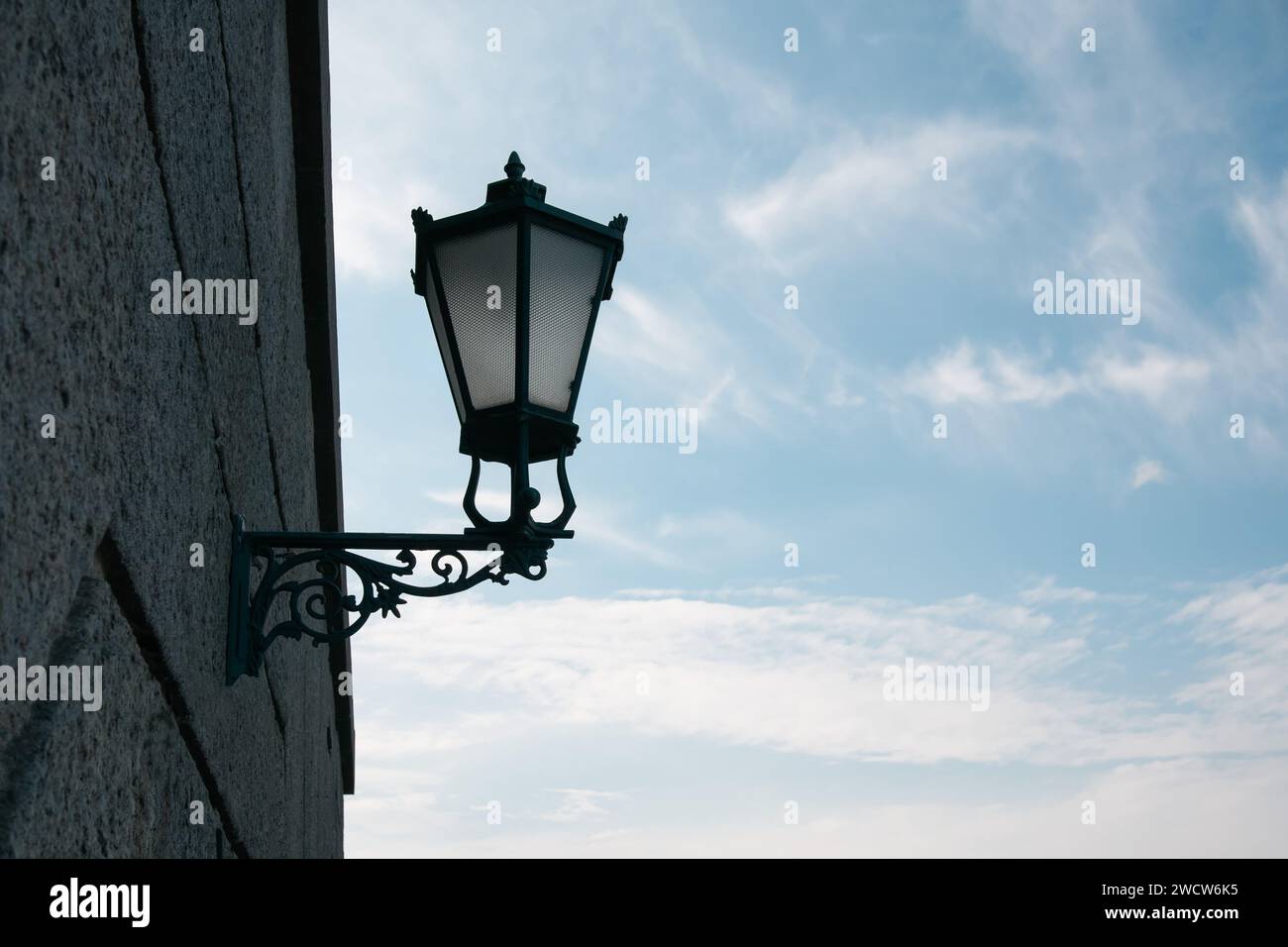 Old street lamp on the wall against the background of the evening blue sky Stock Photo