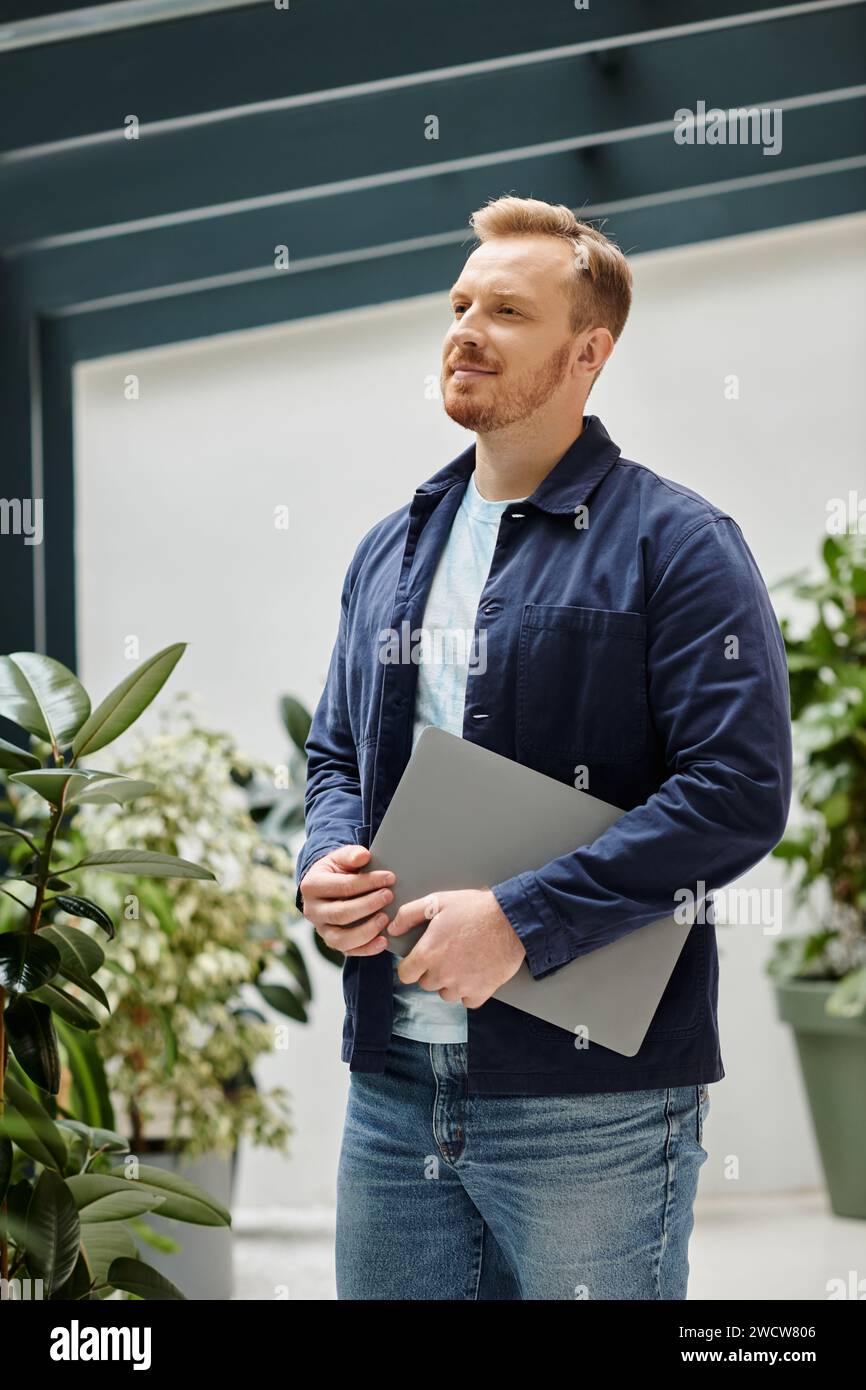 merry good looking architect in everyday clothes holding his laptop and working on his startup Stock Photo