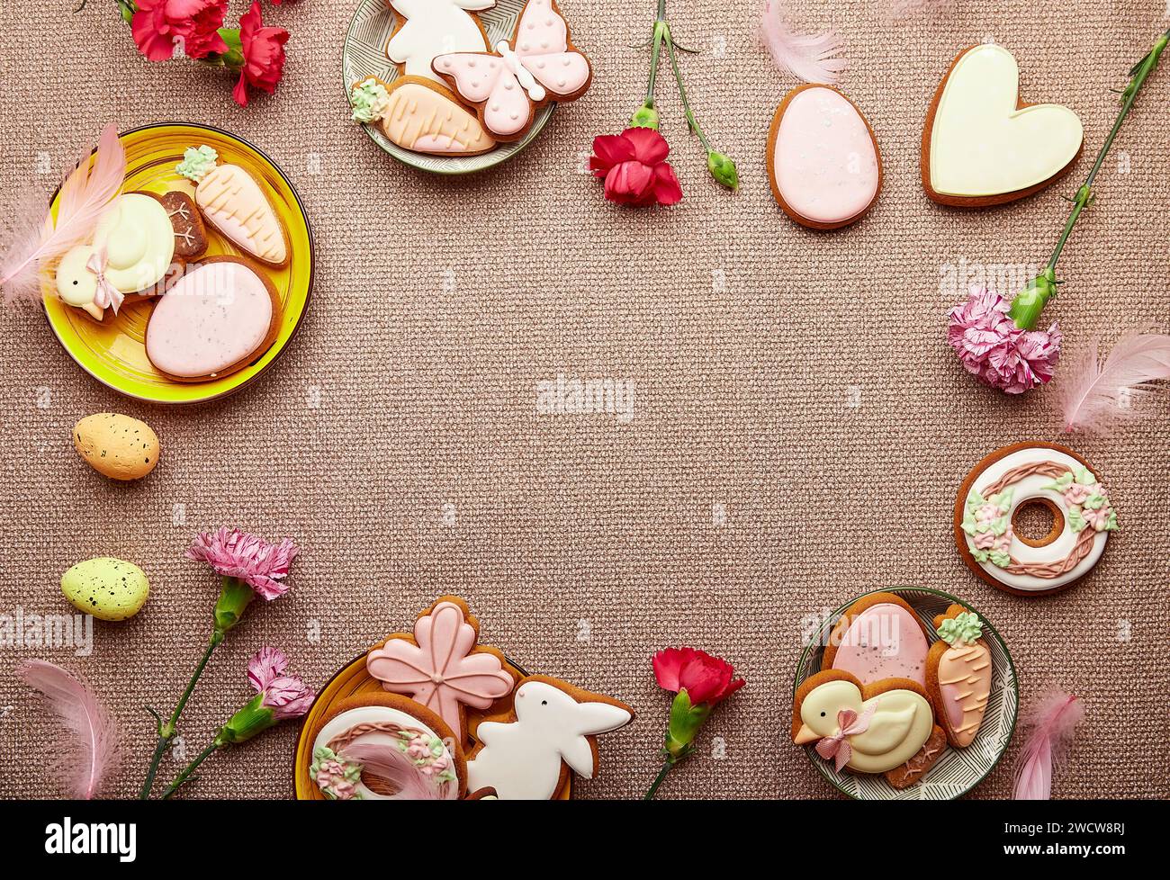 Spring Easter pastel background. Decorated aesthetic Easter cookies, pink flowers with feathers and eggs Stock Photo