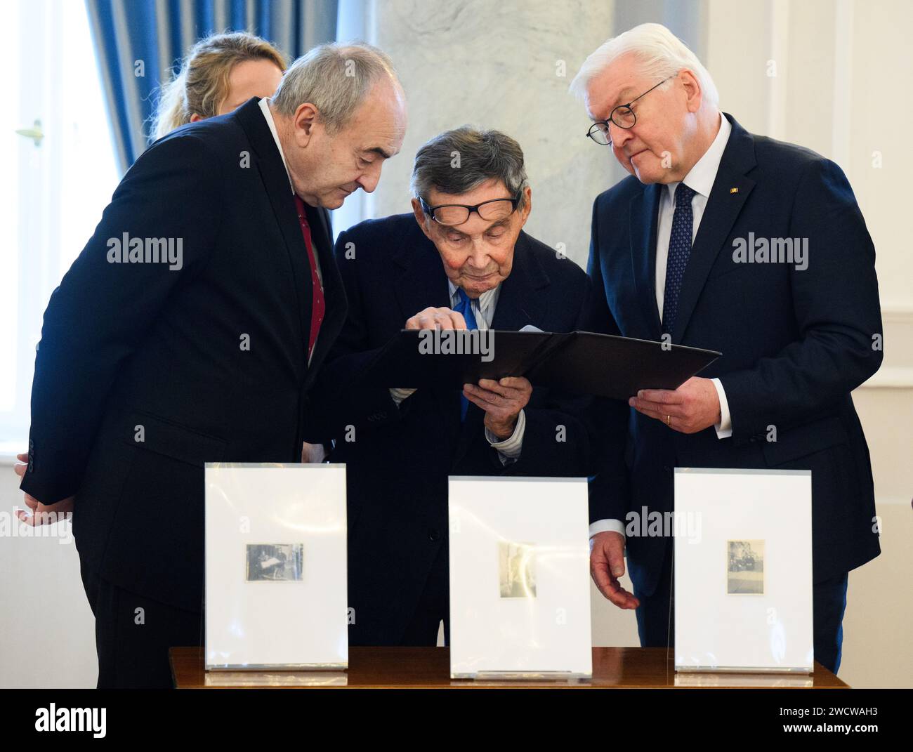 Berlin, Germany. 17th Jan, 2024. Zygmunt Stepinski (l-r), Director of the Polin Museum, Marian Turski, President of the International Auschwitz Committee, and Federal President Frank-Walter Steinmeier look at a photo album during the handover of historical photographs of the German hospital nurse Helmy Spethmann from the Warsaw Ghetto to the Museum of the History of Polish Jews in Warsaw (POLIN) at Bellevue Palace. Credit: Bernd von Jutrczenka/dpa/Alamy Live News Stock Photo