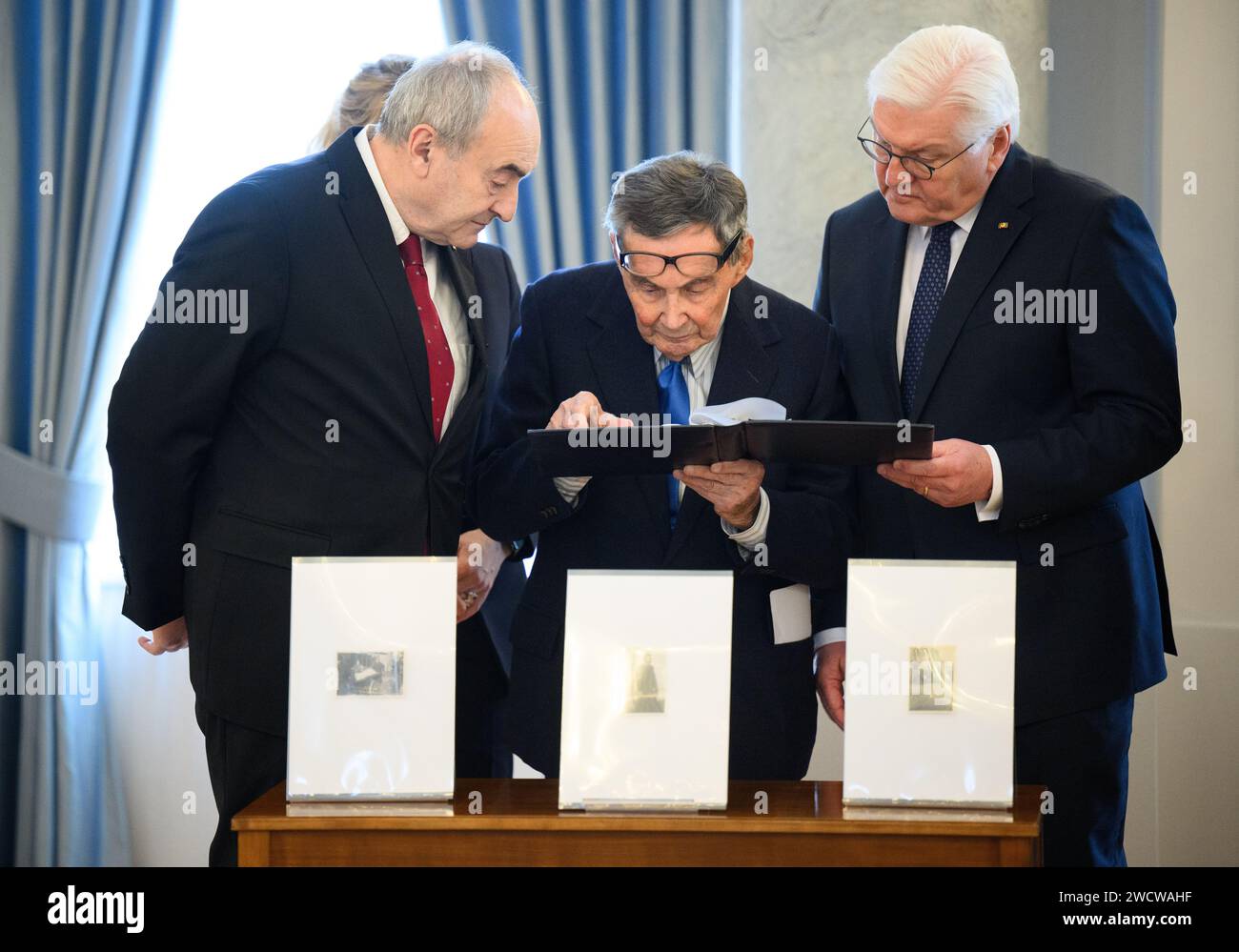 Berlin, Germany. 17th Jan, 2024. Zygmunt Stepinski (l-r), Director of the Polin Museum, Marian Turski, President of the International Auschwitz Committee, and Federal President Frank-Walter Steinmeier look at a photo album during the handover of historical photographs of the German hospital nurse Helmy Spethmann from the Warsaw Ghetto to the Museum of the History of Polish Jews in Warsaw (POLIN) at Bellevue Palace. Credit: Bernd von Jutrczenka/dpa/Alamy Live News Stock Photo