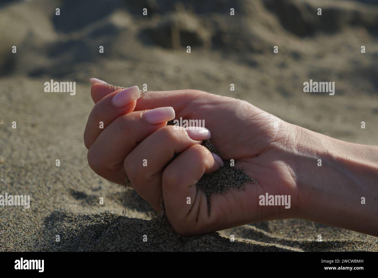 Close-up of a woman's hand releasing falling sand Stock Photo - Alamy